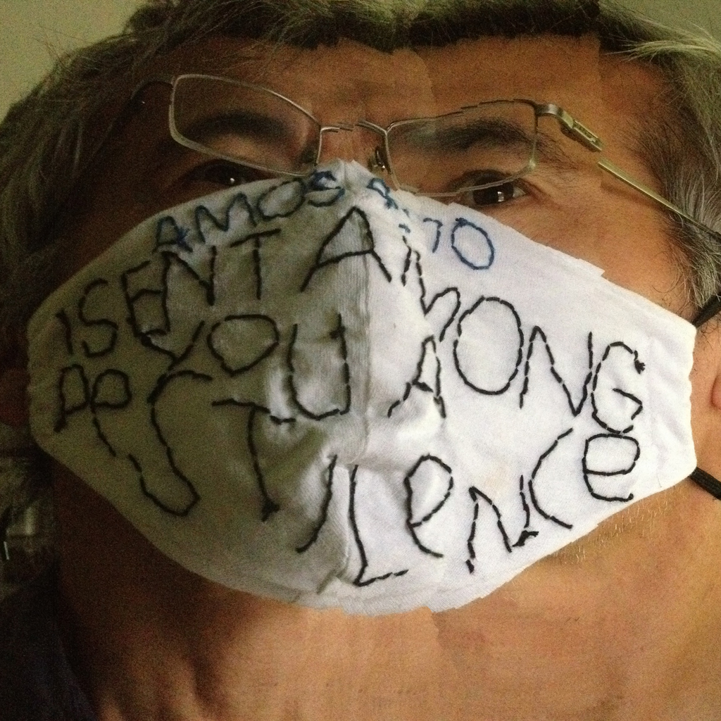 distorted image of my face wearing a homemade protctive mask crudely hand embroidered with a bible verse: Amos monoline grotesk style alphabet>
<p> Amos 4:10, I SENT AMONG YOU A PESTILENCE. An attempt to put an ironically humorous spin on the necessity of wearing a mask in everyday life and inspired bthe work of quilt artist Rosie Lee Tomkins.