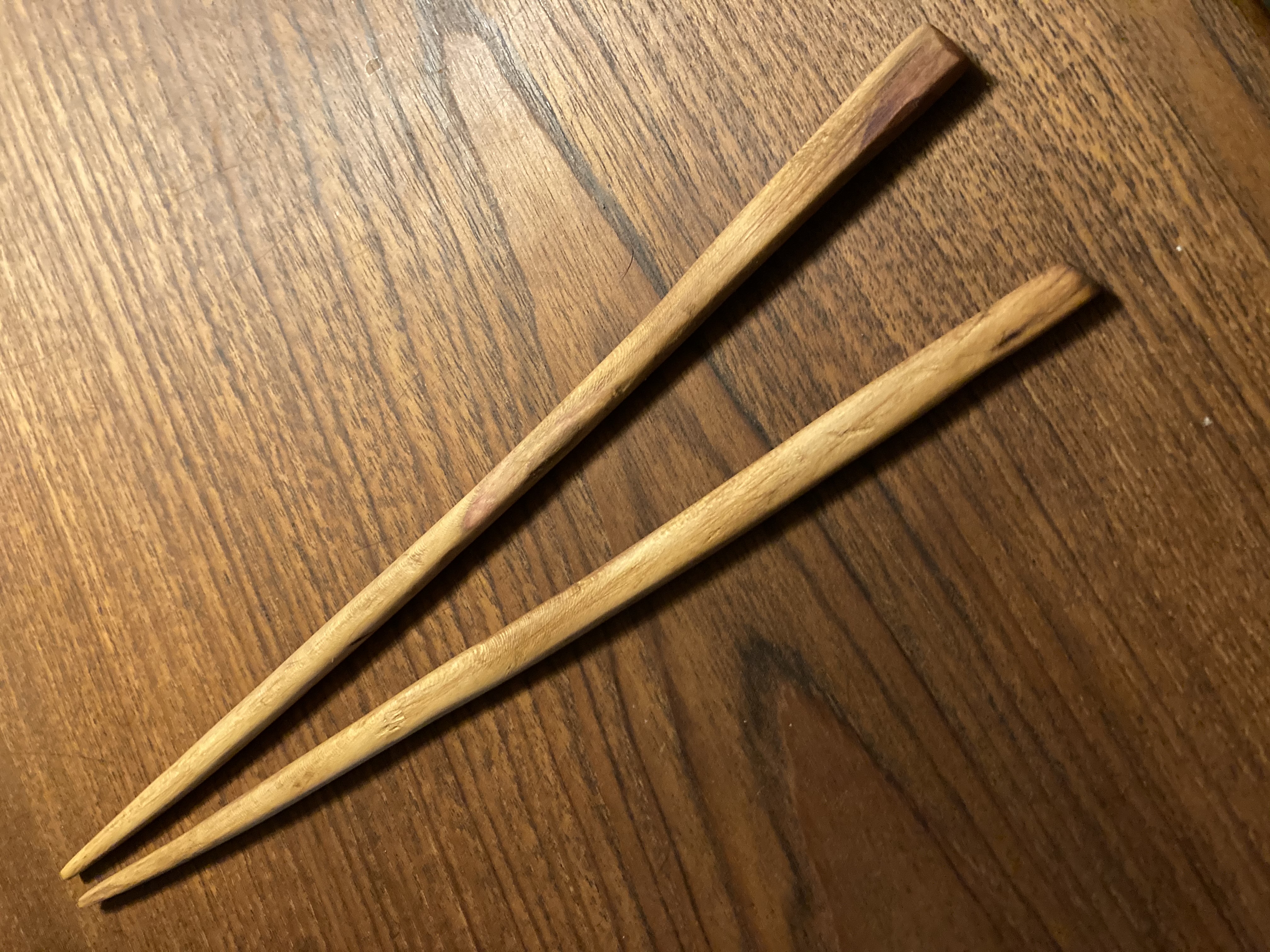 image of a pair of handmade chopsticks on a woodgrain background.